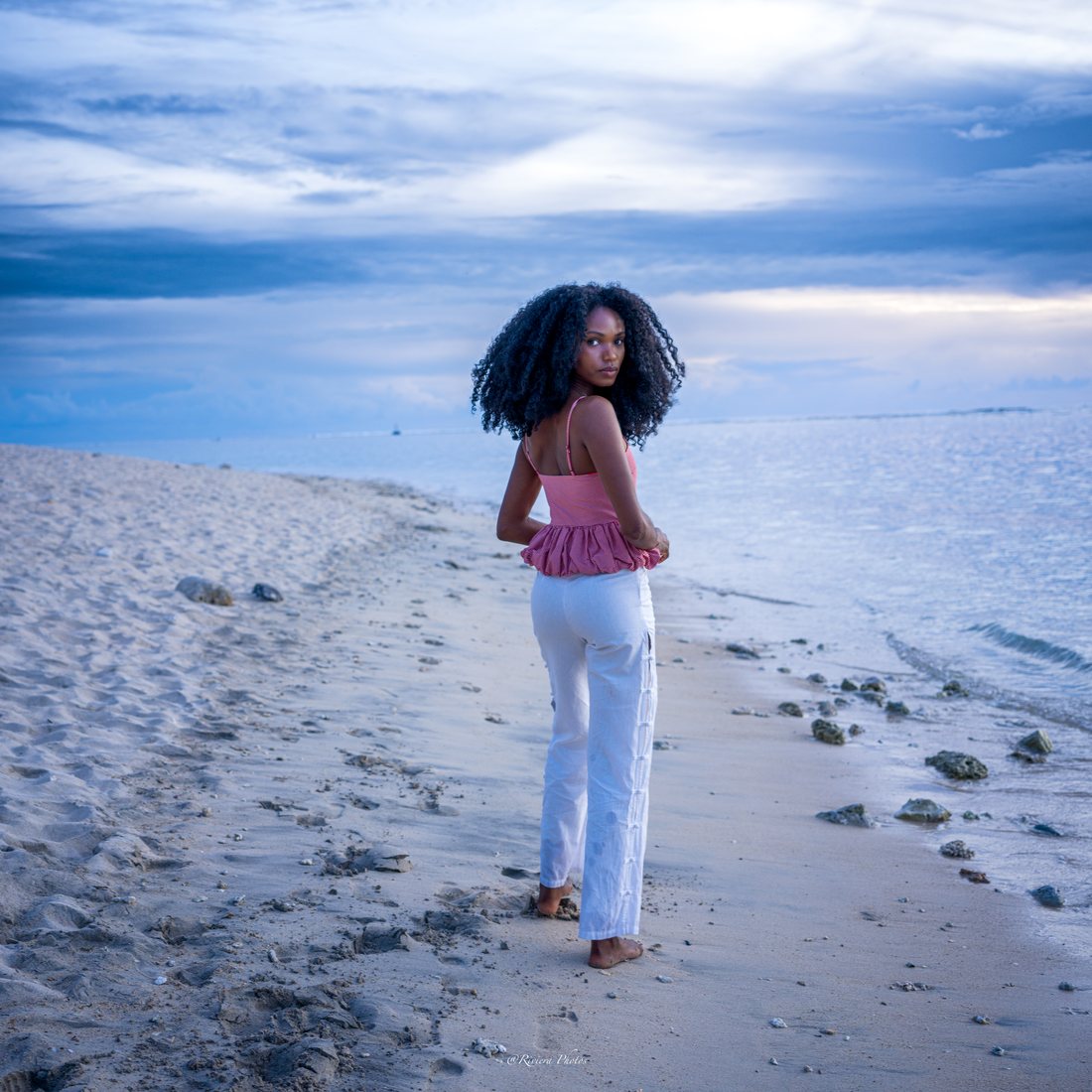 Jeune femme marchant pieds nus sur la plage, se retournant vers l'objectif.