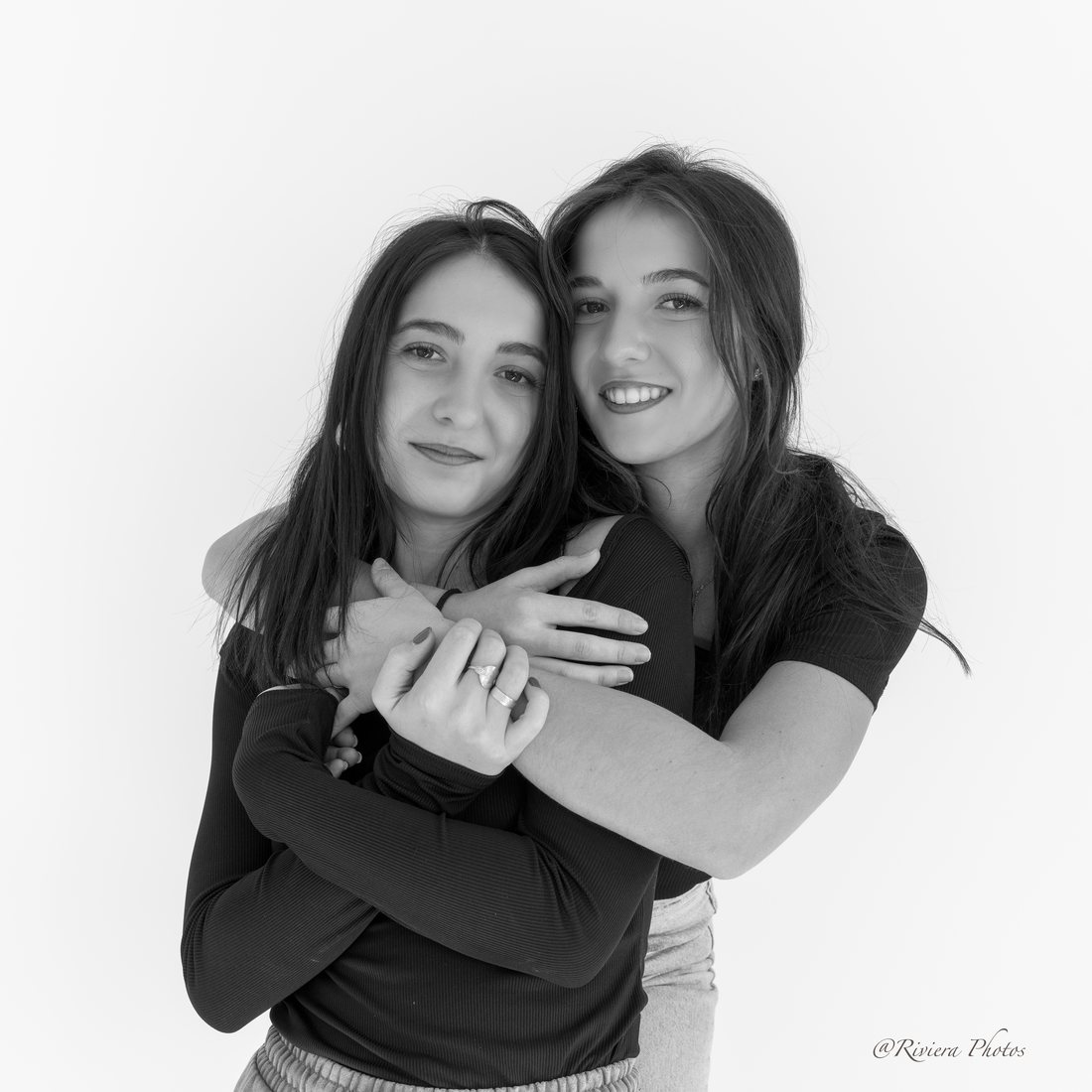 Portrait en noir et blanc de deux jeunes femmes enlacées, souriantes